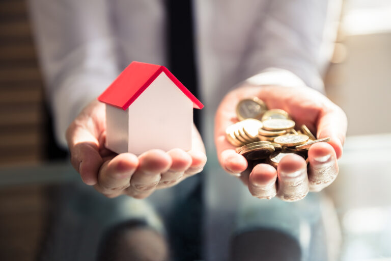 Businessperson Holding House Model And Golden Coins