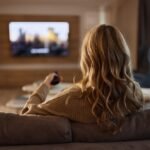 Woman relaxing on a sofa at home while choosing a TV show to watch