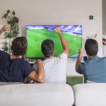A person browsing movie tiles on a TV screen while holding a remote control