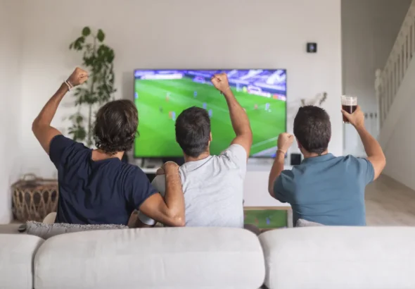 A person browsing movie tiles on a TV screen while holding a remote control