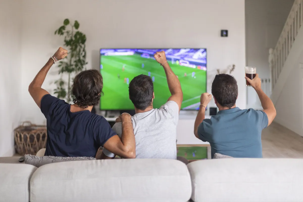 A person browsing movie tiles on a TV screen while holding a remote control