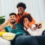 Family enjoying popcorn while watching a movie together at home