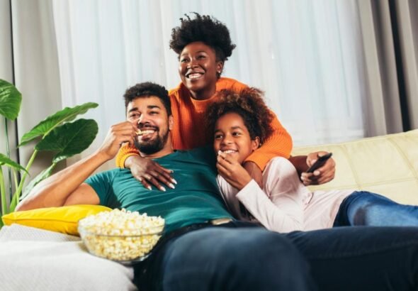 Family enjoying popcorn while watching a movie together at home