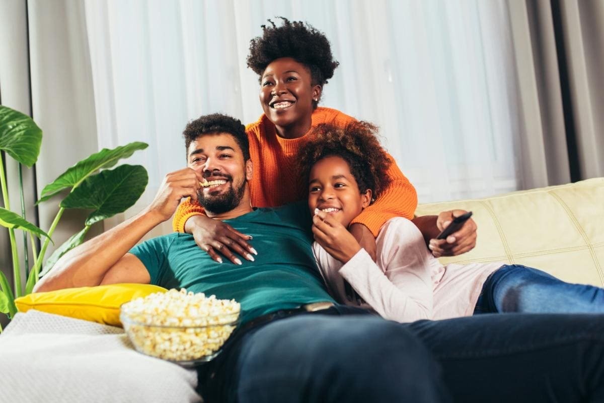 Family enjoying popcorn while watching a movie together at home